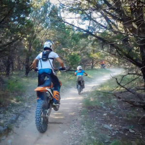 A mother riding dirt bikes with her son.