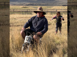 A Man riding a min-bike in a field.