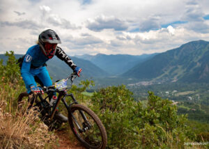 Mountain biker on a trail on the side of a mountain while racing.