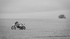 A lonely motorcycle sitting in a field.