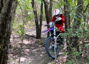 Dirt Bike rider riding between tight trees on a piece of singletrack.