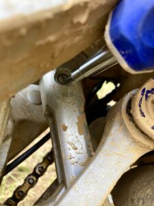 Screw driver setting shock rebound on a dirt bike.