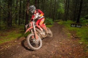 Enduro racer showing proper standing form while leaning their gasgas over in an enduro turn.