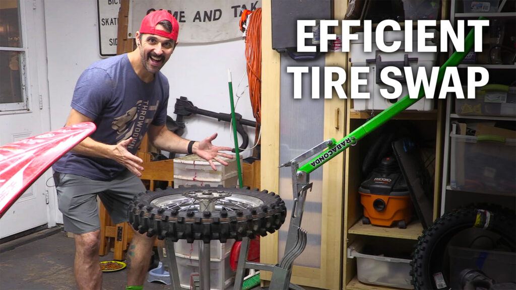 Dirt Bike rider demonstrating efficient rear tire change process using a Rabaconda Dirt Bike Tire Changer tool.