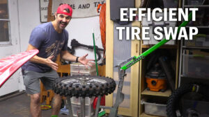 Dirt Bike rider demonstrating efficient rear tire change process using a Rabaconda Dirt Bike Tire Changer tool.