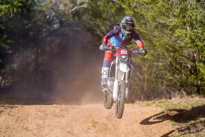 Fantic XE 300 rider jumping a small rise during local enduro race