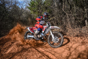 Dirt bike racer blasting a dusty corner on a Fantic XE300 two stroke.