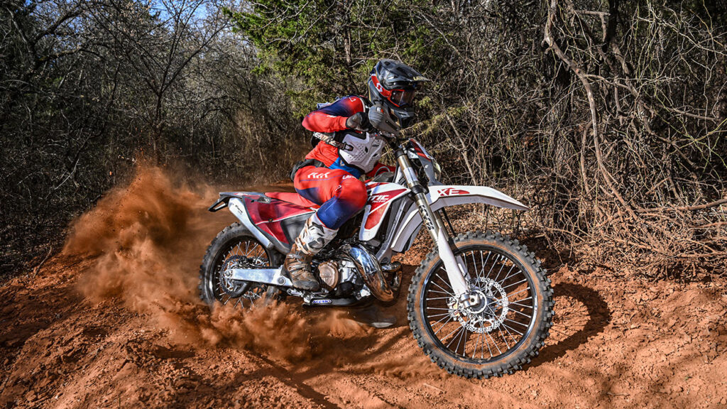 Dirt bike racer blasting a dusty corner on a Fantic XE300 two stroke.
