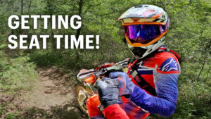 Dirt bike riders getting seat time on Texas singletrack, fist bumping during a two‑stroke throttle therapy session.
